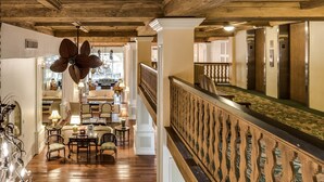 Eine Hotelhalle mit Holzböden, einem Kronleuchter und einer Sitzecke mit Tischen und Stühlen.