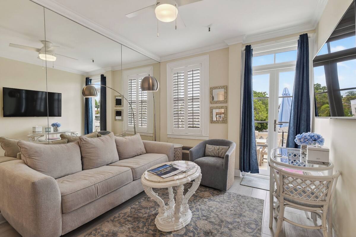 Ein Wohnzimmer mit Sofa, Sessel, rundem Tisch und Fernseher.