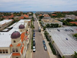 Vista aérea de una ciudad costera con edificios de techos rojos y estructuras abovedadas, una calle amplia y automóviles estacionados.
