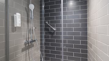 A shower area with a glass door, a handheld showerhead, and a wall-mounted control panel.