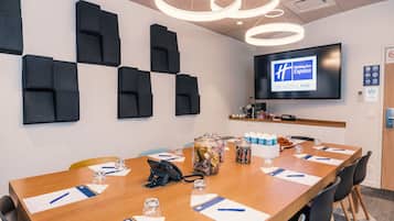 Ett konferensrum med ett långt bord, stolar, en projektorduk och en skylt för Holiday Inn Express.