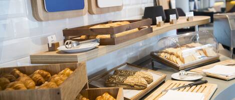 A bakery display with various baked goods and a knife on a cutting board.