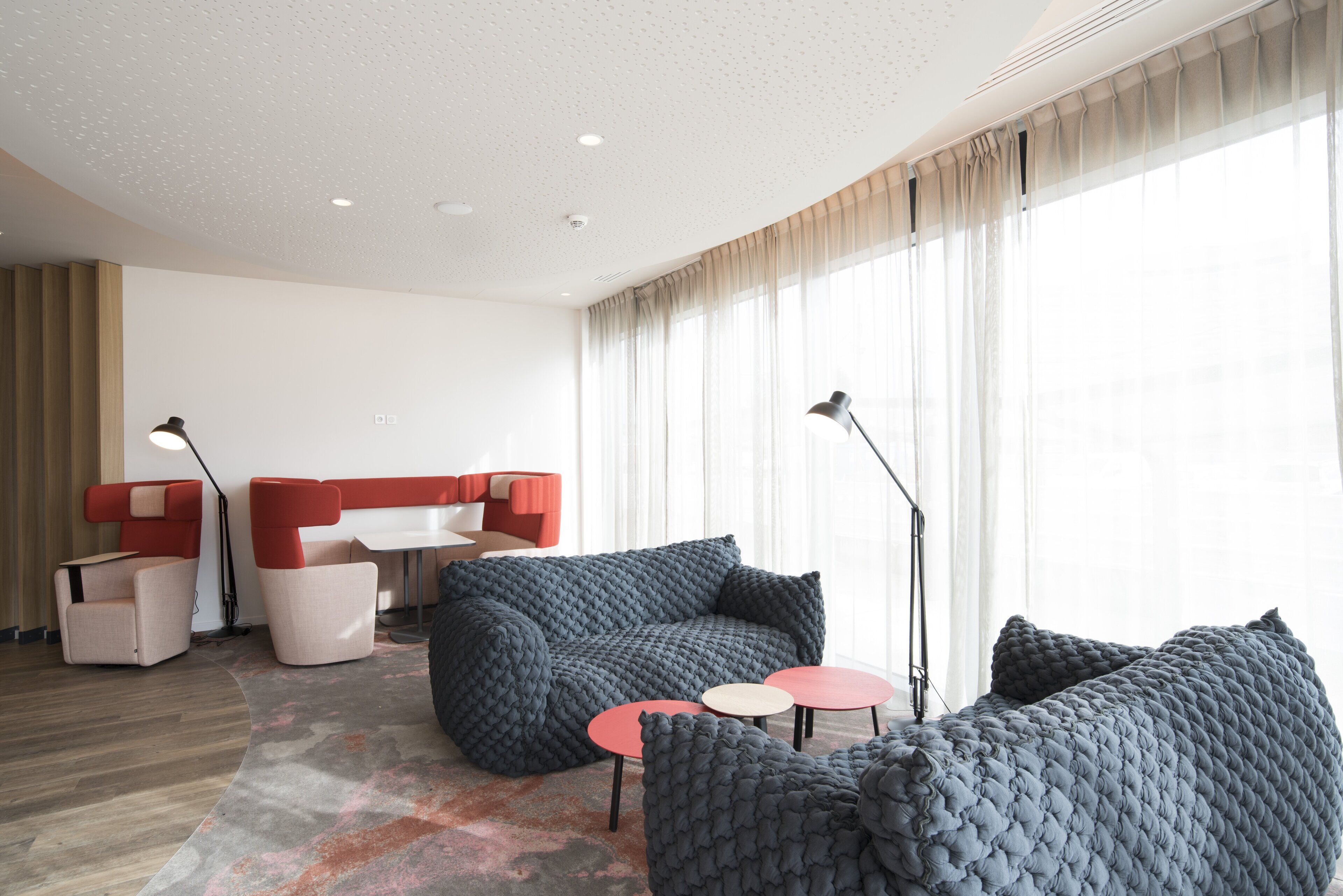 A modern living room with a sectional sofa, two armchairs, a small coffee table, and a floor lamp.