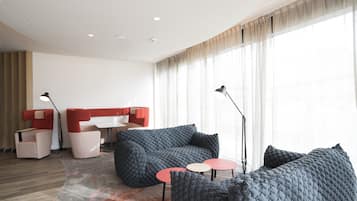 A modern living room with a sectional sofa, two armchairs, a small coffee table, and a floor lamp.