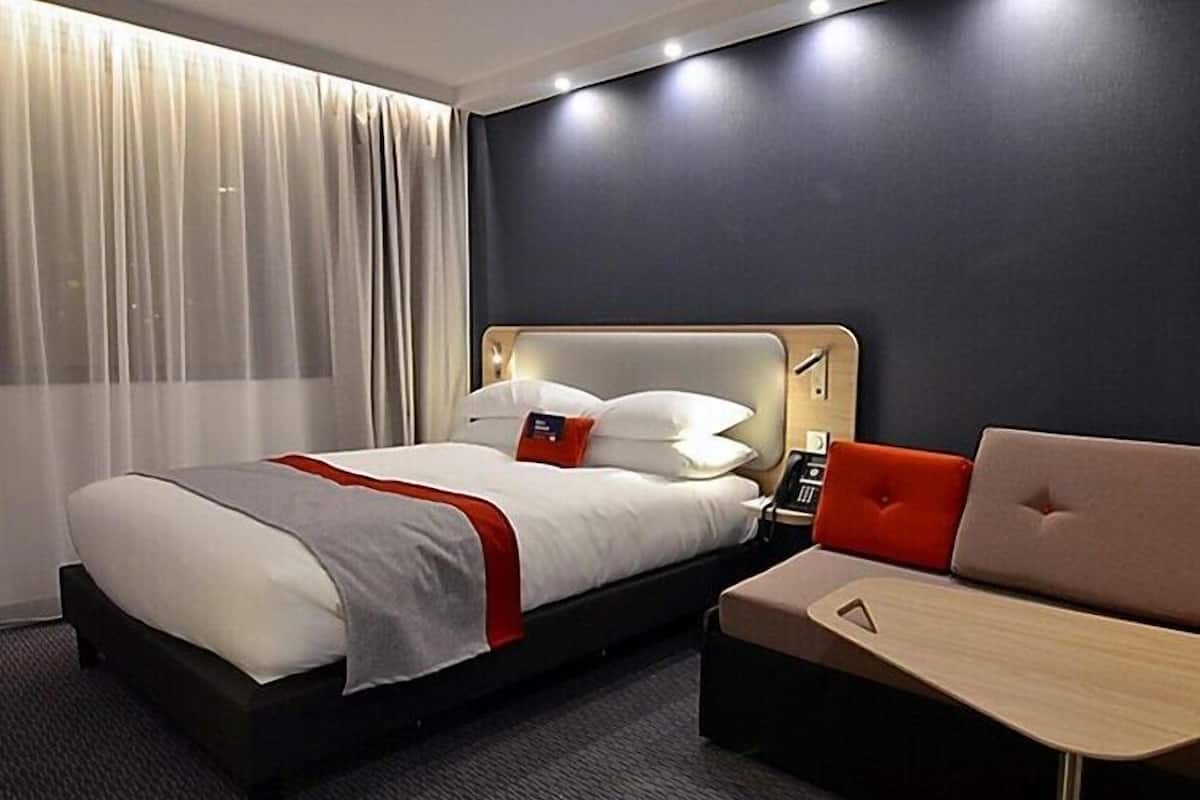 Ein Hotelzimmer mit einem Bett, einem Nachttisch und einem Schlafsofa.