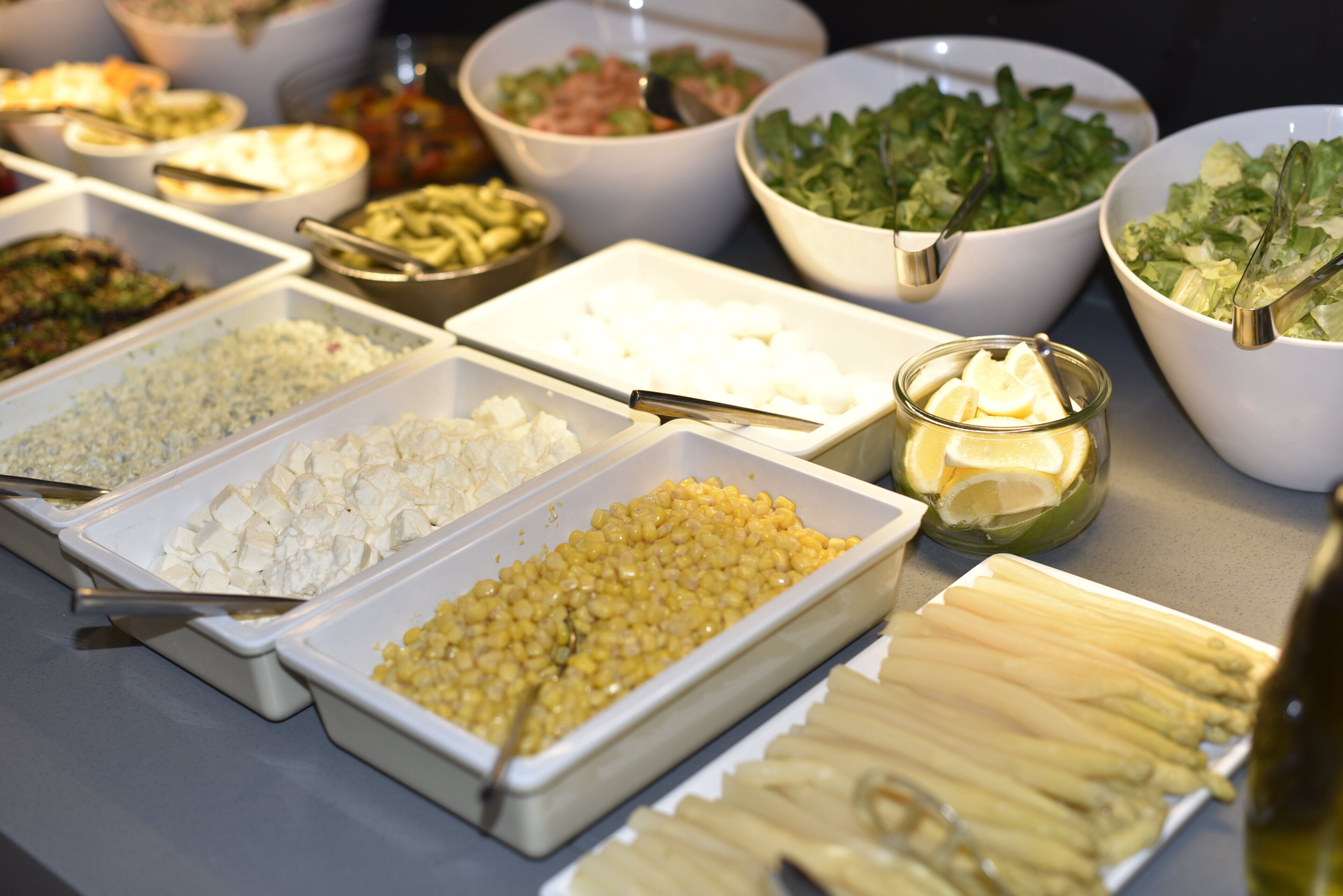 Un bufé con diversos alimentos, incluyendo pasta, verduras y ensaladas.