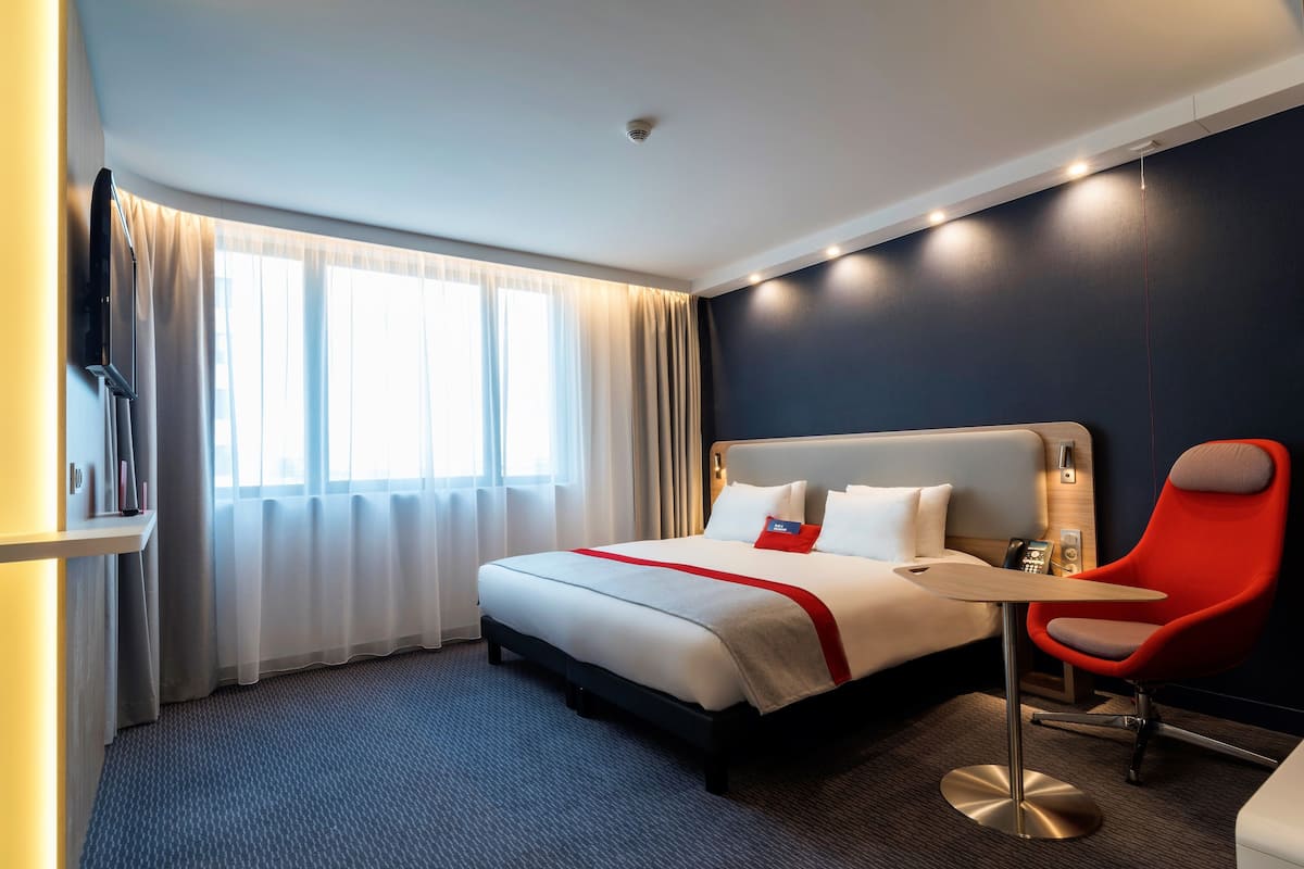 Ein Hotelzimmer mit einem Bett, einem Schreibtisch, einem Sessel und einem Fernseher.