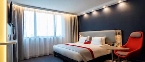 Una habitación de hotel con una cama, un escritorio, una silla y un televisor.