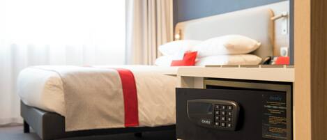 Une chambre d’hôtel avec un lit, une table de chevet dotée d’un panneau de commande et une fenêtre avec des rideaux.
