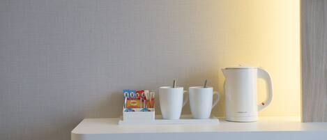 A white shelf with a coffee maker, two white cups, and a coffee pod holder.