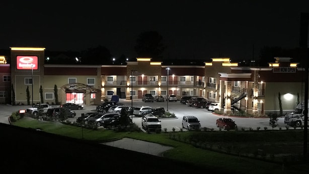 Een hotel met meerdere verdiepingen, een parkeerplaats en een bord dat aangeeft dat het geopend is.