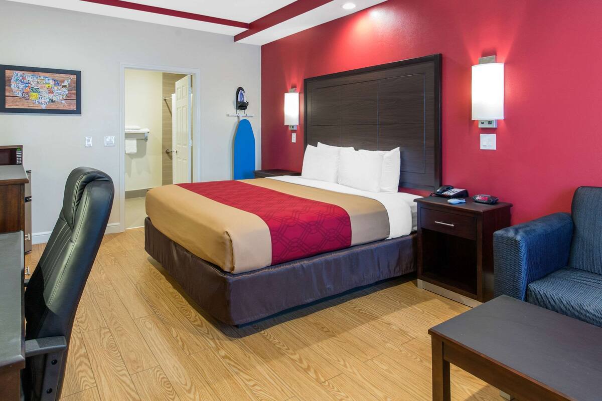 A hotel room with a bed, a desk, a chair, and a sofa.