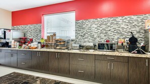 A modern kitchen with dark wood cabinets, a red accent wall, and a patterned backsplash. - Econo Lodge Inn & Suites Houston Willowbrook (Houston)