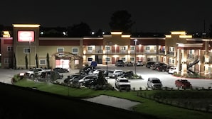 Een hotel met meerdere verdiepingen en een parkeerplaats.