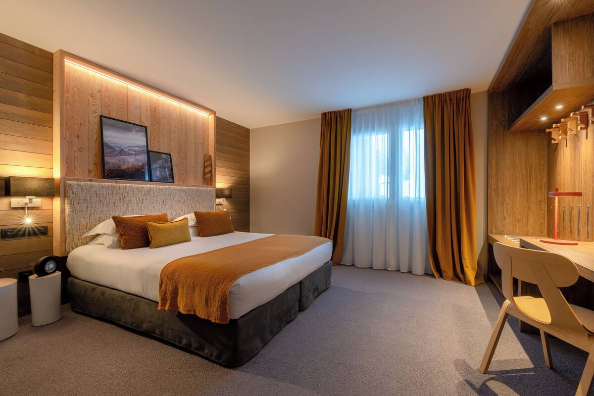 Ein modernes Hotelzimmer mit einem großen Bett, einem Schreibtisch und Blick ins Freie.