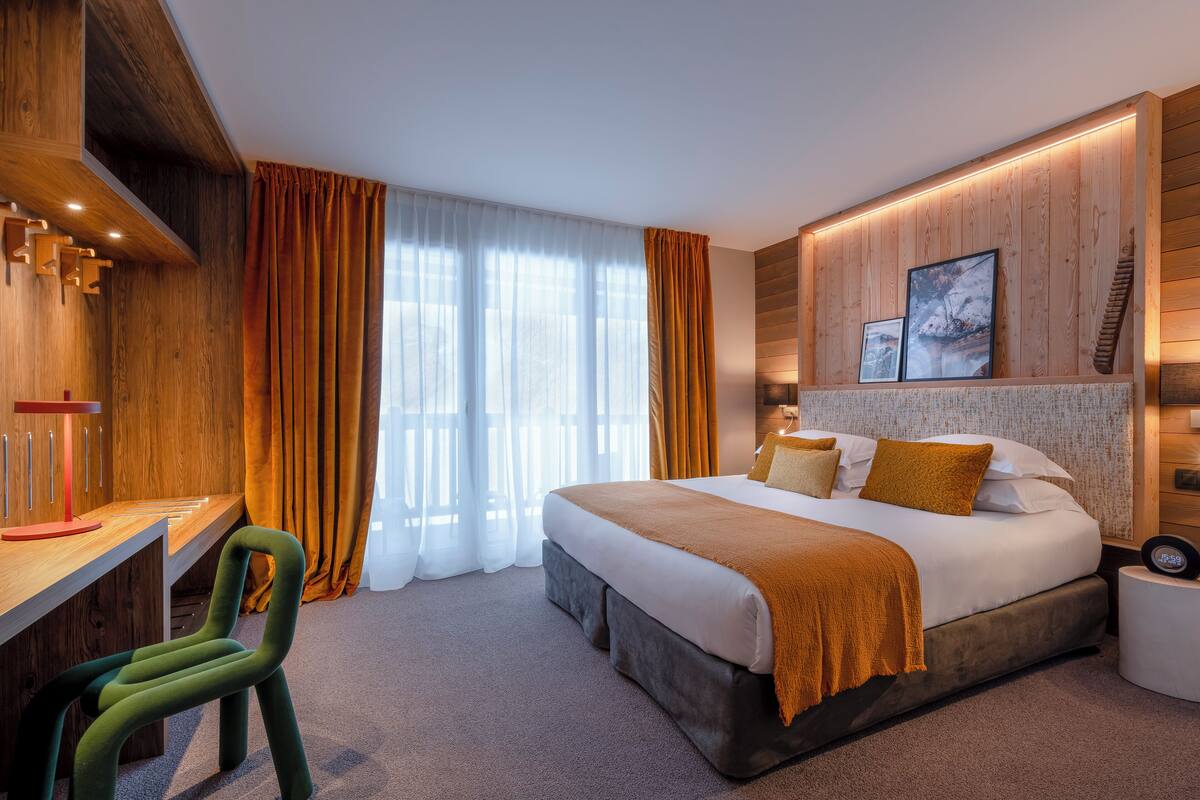 Ein modernes Hotelzimmer mit einem großen Bett, einem Schreibtisch und einem Sessel.