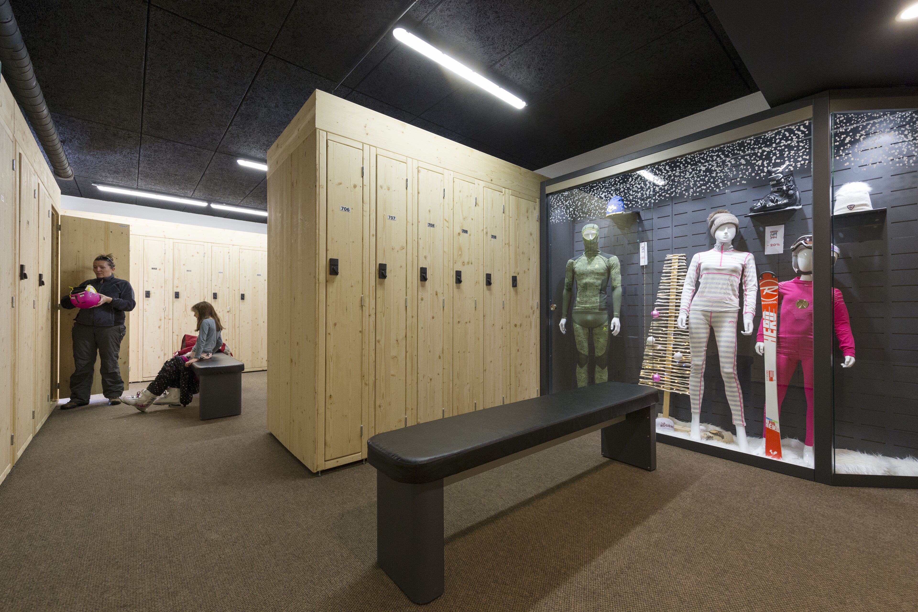 A locker room with wooden lockers, a bench, and mannequins displaying athletic wear.