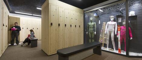 A locker room with wooden lockers, a bench, and mannequins displaying athletic wear.