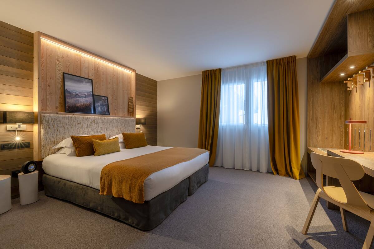 Ein modernes Hotelzimmer mit einem großen Bett, einem Schreibtisch und Blick ins Freie.