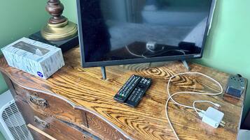 A wooden dresser with a television, remote controls, and a power strip.