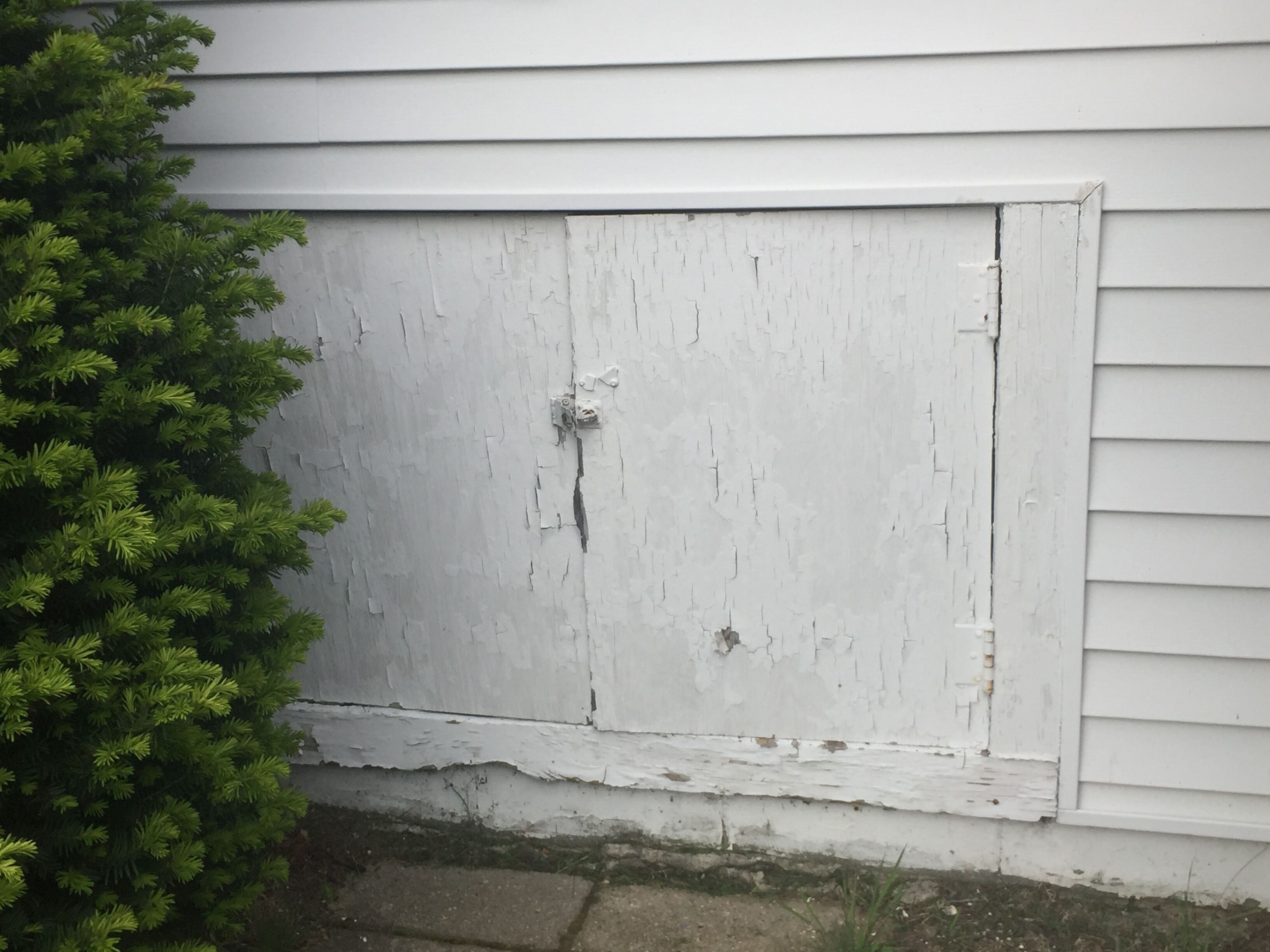 A white garage door with visible wear and a small utility box to the left.