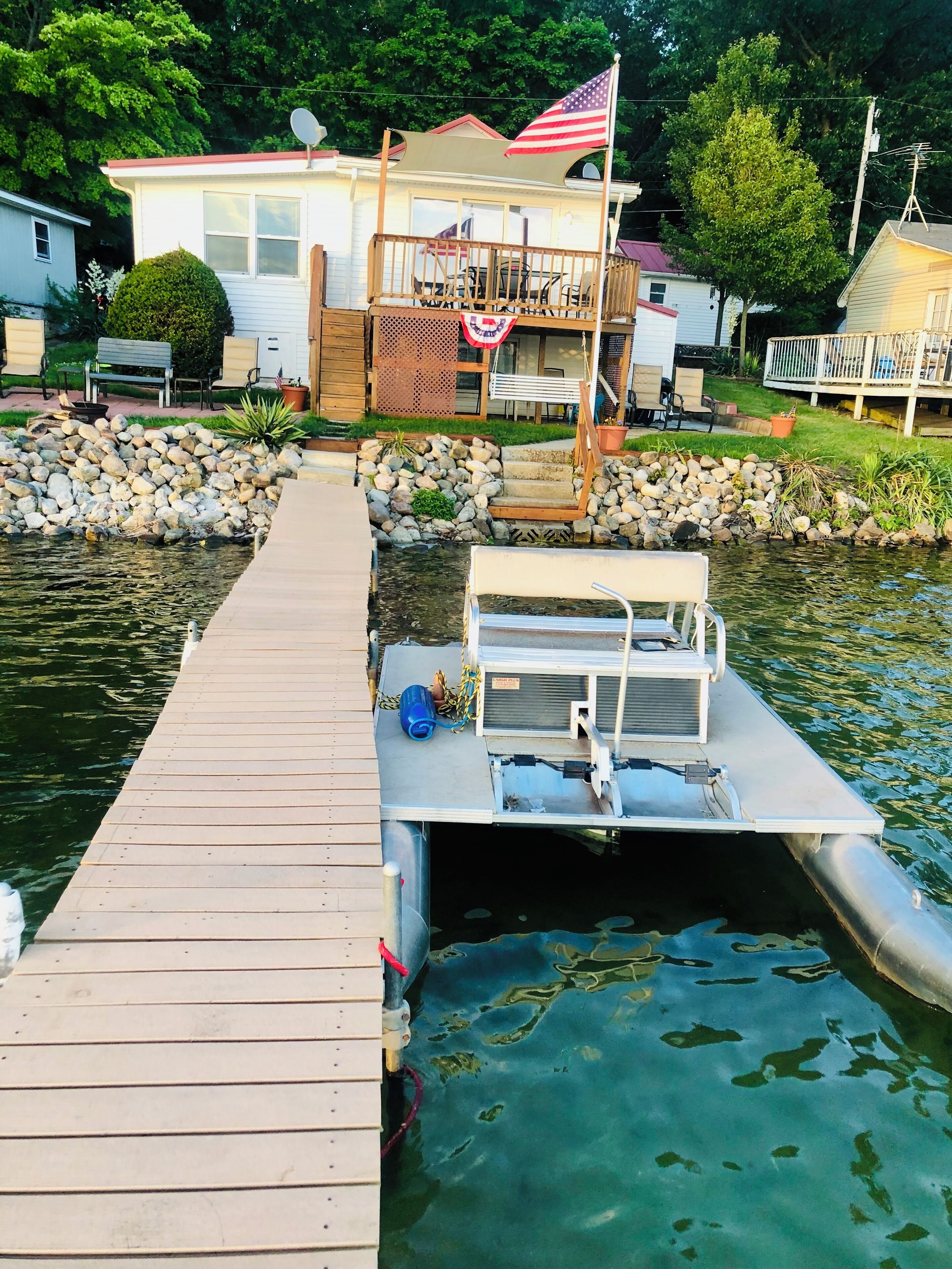 A dock extending into a body of water with a house in the background.