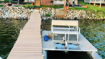 A dock extending into a body of water with a house in the background.