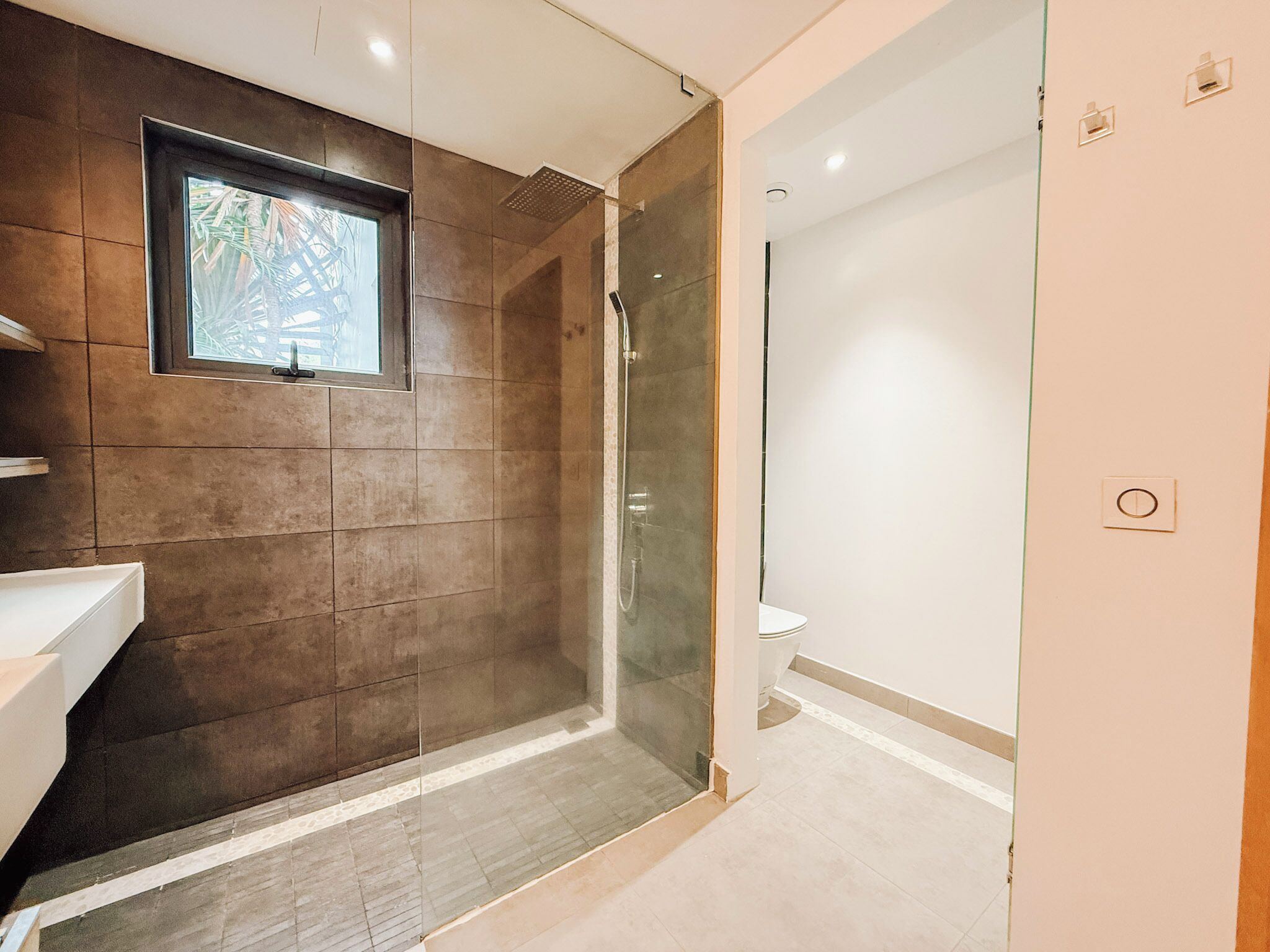A modern bathroom with a glass shower enclosure, a sink, and a toilet.