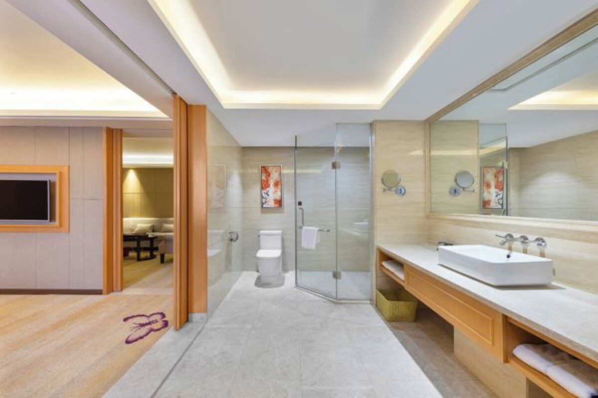 Un baño moderno con cabina de ducha de vidrio, un espejo grande y un lavabo con tocador.