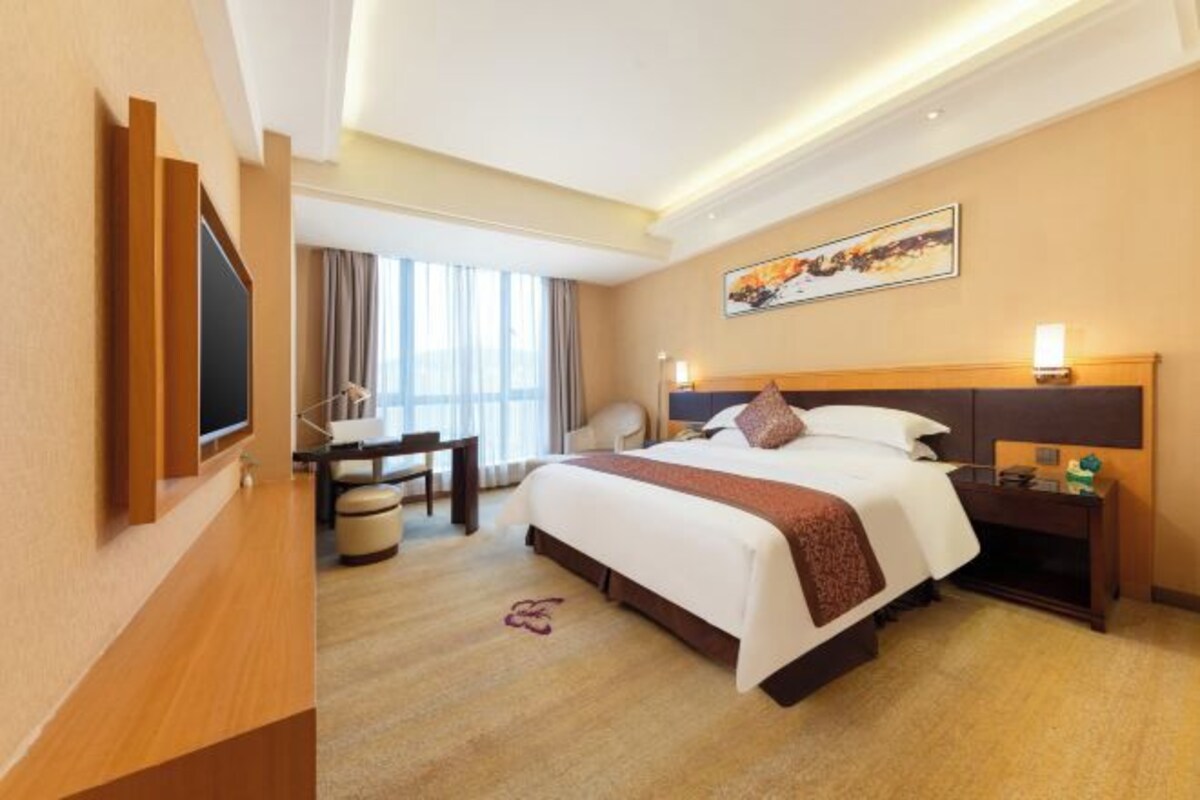 Una habitación de hotel con una cama grande, un escritorio, una silla y un televisor.