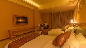 A hotel room with two beds, a desk with a lamp, a picture on the wall, and a curtain. - Grand Garden Hotel (Shaoguan)