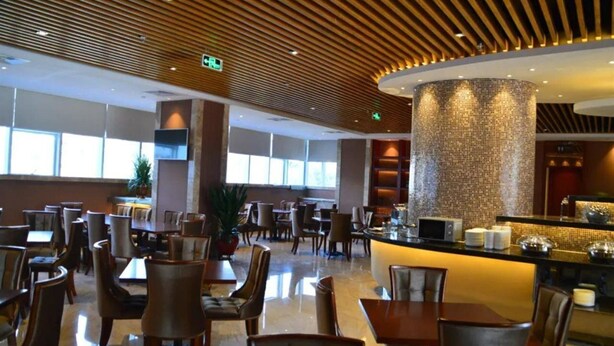 Vestíbulo moderno de hotel con techo de madera, una columna central y una zona de bar.