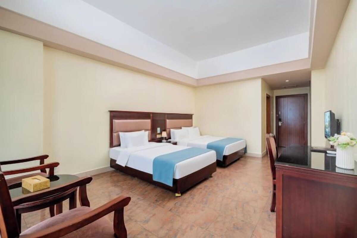Une chambre d’hôtel avec deux lits, un bureau, une chaise et un téléviseur.