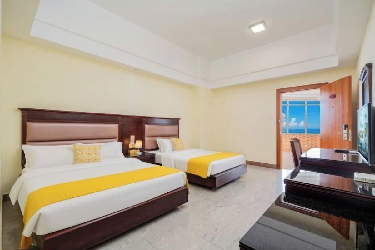 Habitación de hotel con dos camas, un escritorio y un televisor.
