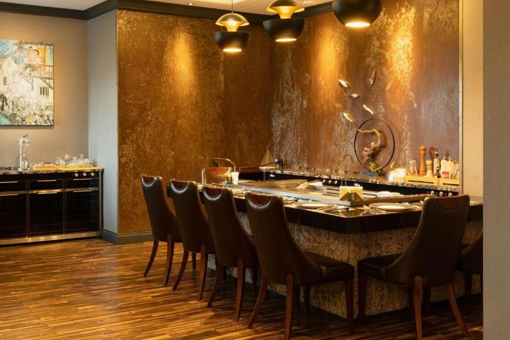 A bar area with a bar counter, chairs, and a wall with a textured finish.
