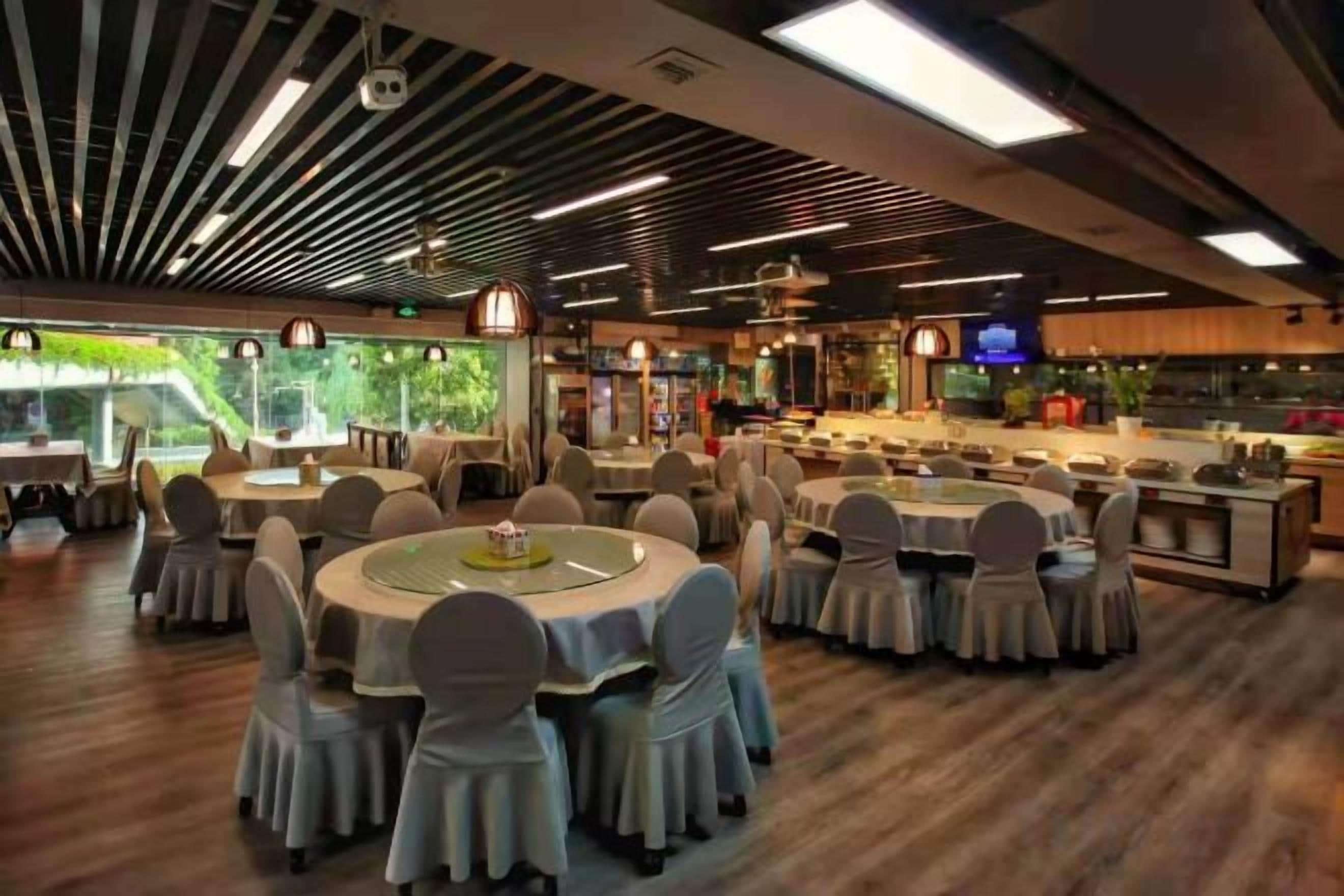 A restaurant with round tables, chairs, and a bar area.