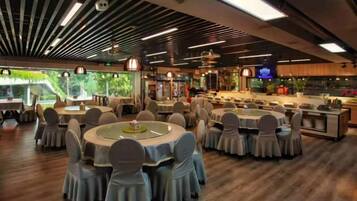 A restaurant with round tables, chairs, and a bar area.