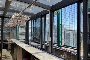 Una cocina moderna con una encimera larga, ventanas amplias y una lámpara colgante.