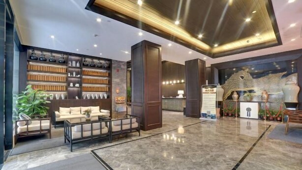 A modern lobby with a marble floor, seating area with sofas and a coffee table, a reception desk, and a decorative wall with shelves. - Fuzhou Boerya Wuyi Hotel (Fuzhou)