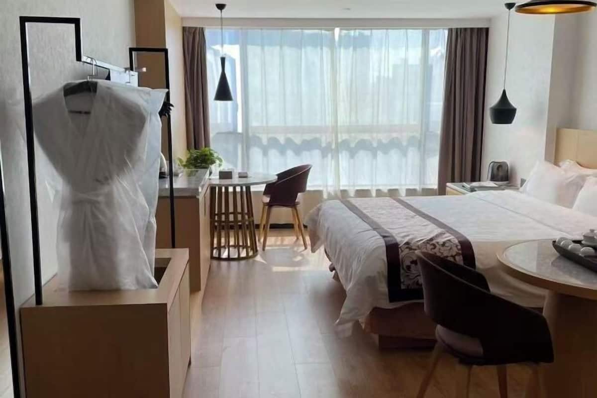 A hotel room with a bed, a desk, a chair, and a window with curtains.