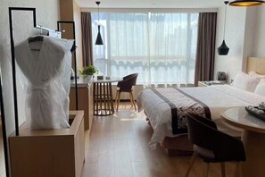 Una habitación de hotel con cama, escritorio, silla y ventana con cortinas.