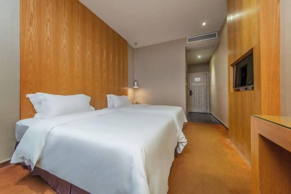 Une chambre d’hôtel avec un grand lit, une télévision, un bureau et une porte donnant sur une autre pièce.