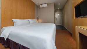 Hotellihuone, jossa on sänky, seinälle asennettu televisio ja käyt ävä, joka johtaa toiseen huoneeseen.