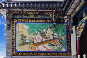 A traditional Chinese building with ornate decorations and a mural depicting two figures playing a stringed instrument. - Jiangnanju Boutique Hotel (Dali City)