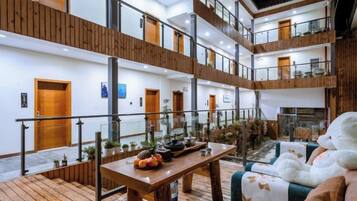 A multi-level hotel lobby with a central wooden table, seating areas, and a staircase.
