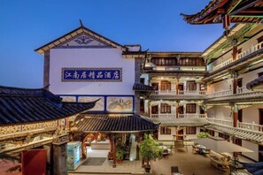 Un patio tradicional con un edificio que tiene un letrero en idioma extranjero, varios niveles y un tejado de baldosas.