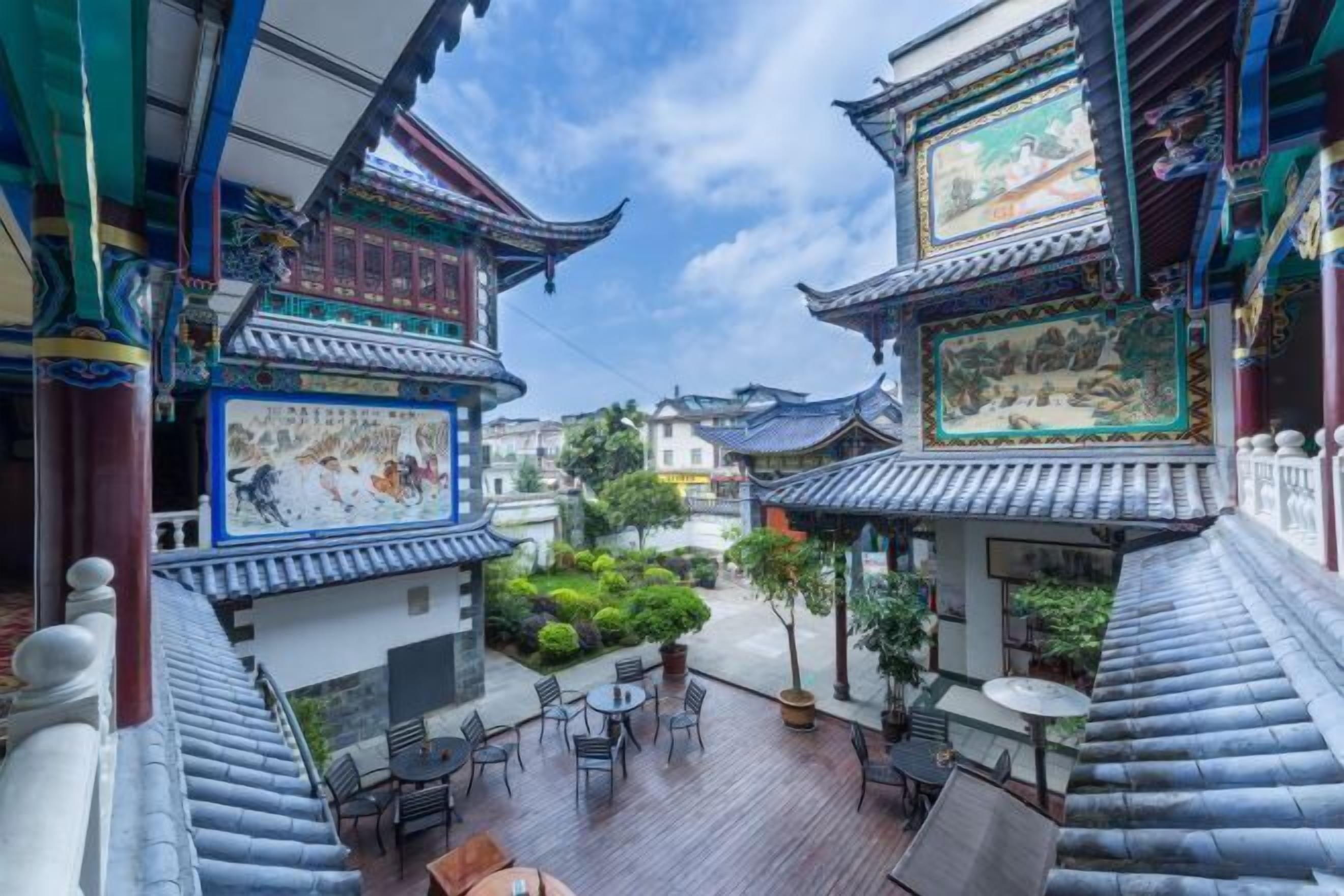 A traditional courtyard with tiled roofs, a mural, and outdoor seating.