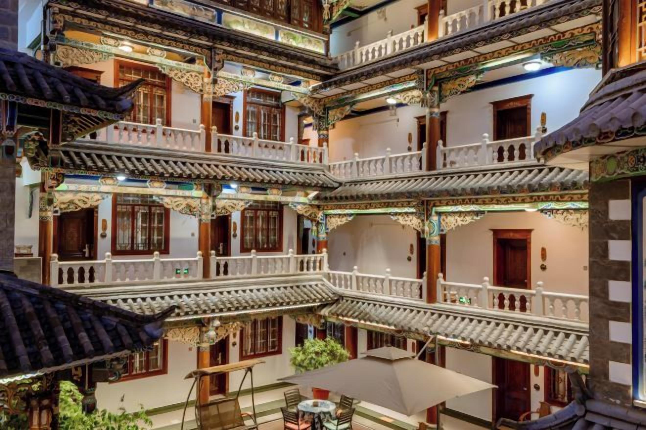 A traditional multi-story building with balconies, wooden railings, and a central courtyard with a table and chairs.