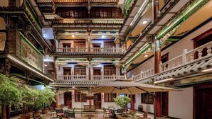 Un bâtiment traditionnel à plusieurs étages, doté de balcons, de places assises à l’intérieur et de plantes en pot.