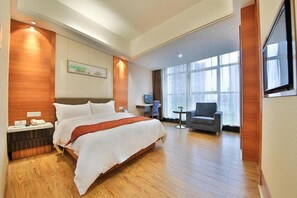 A hotel room with a large bed, a desk, a chair, and a TV. - Hong Yang Hotel (Shenzhen)